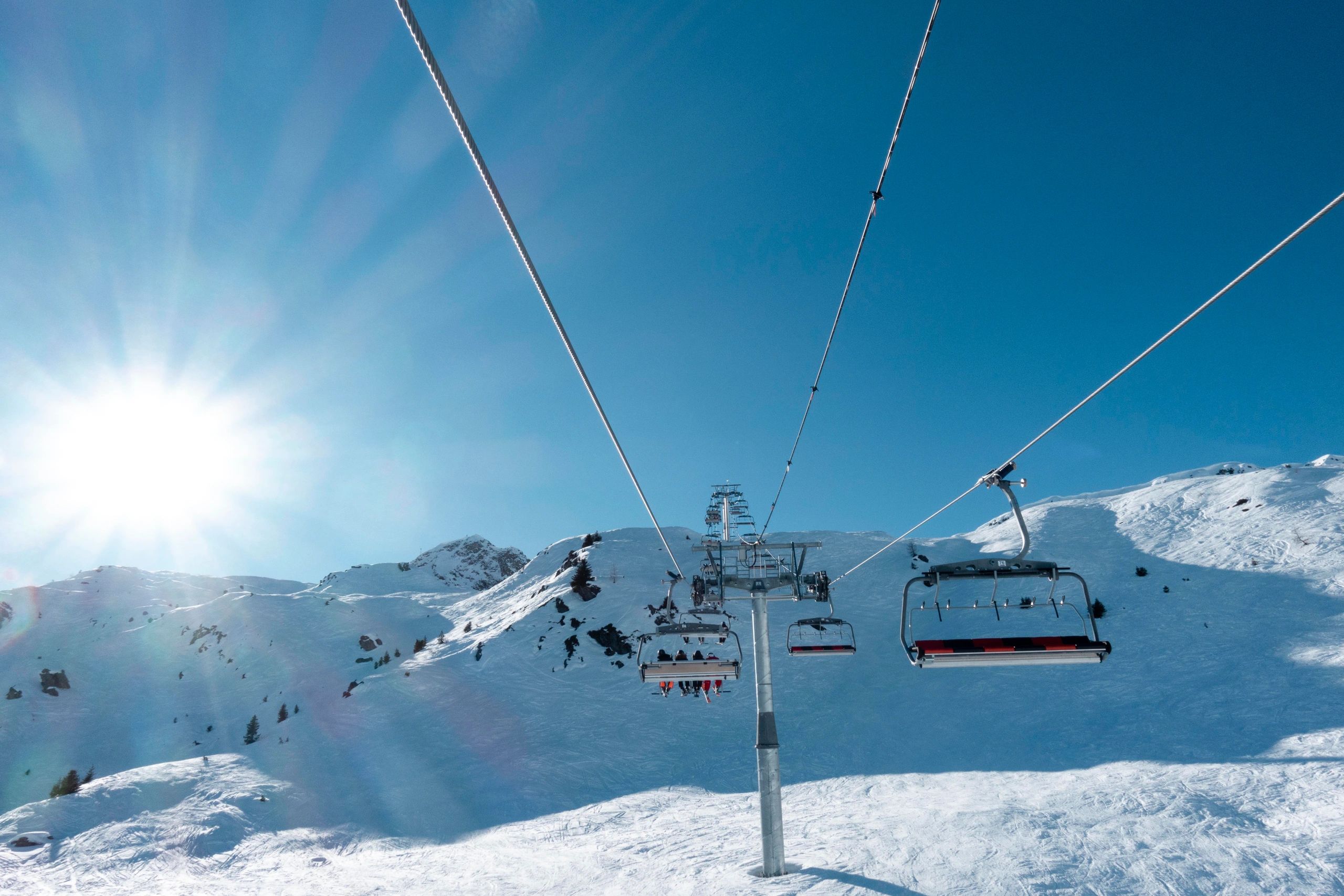 Ski lift traveling above snowy slopes on a sunny day