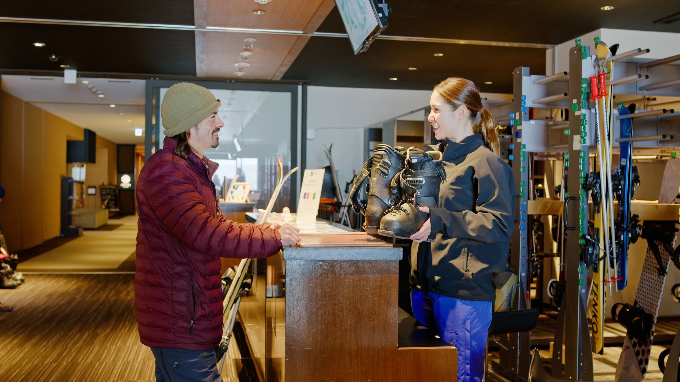 Ski rental shop staff holding ski boots for a customer