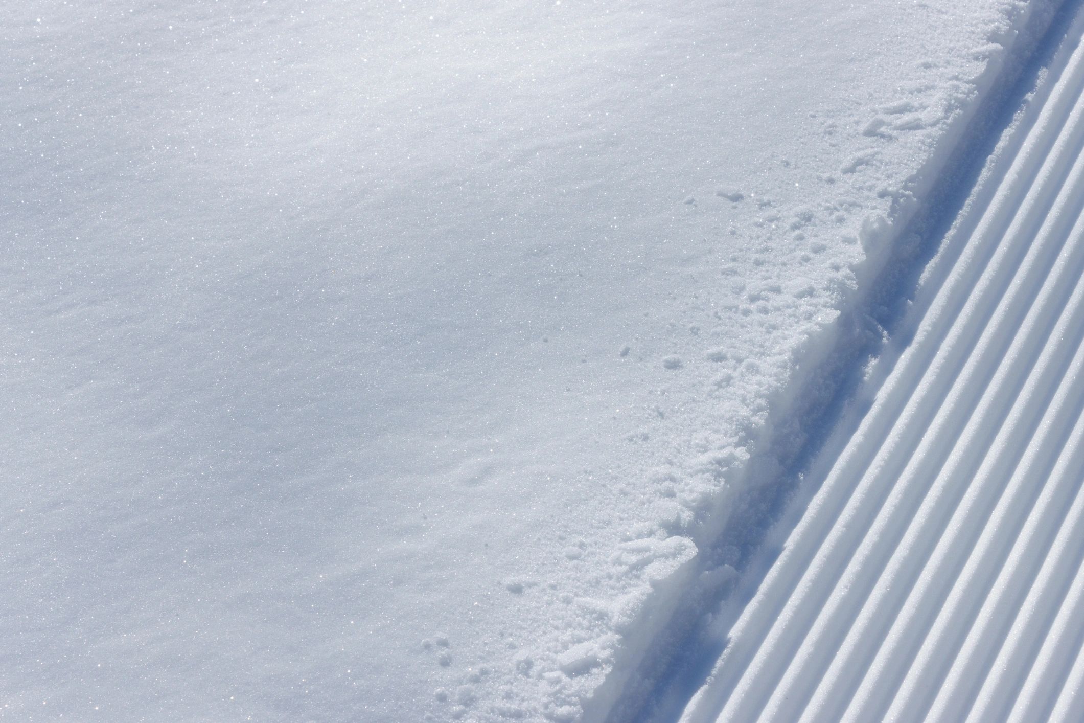 Edge of a groomed ski slope with fresh snow