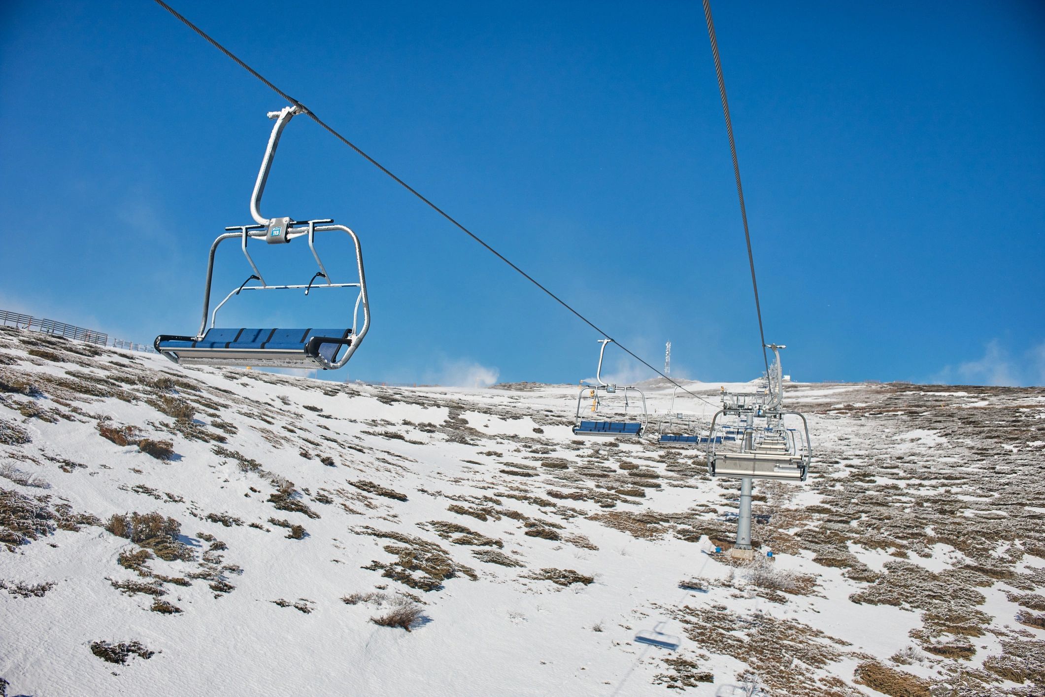 Empty chairlifts ascending a snowy mountain slope