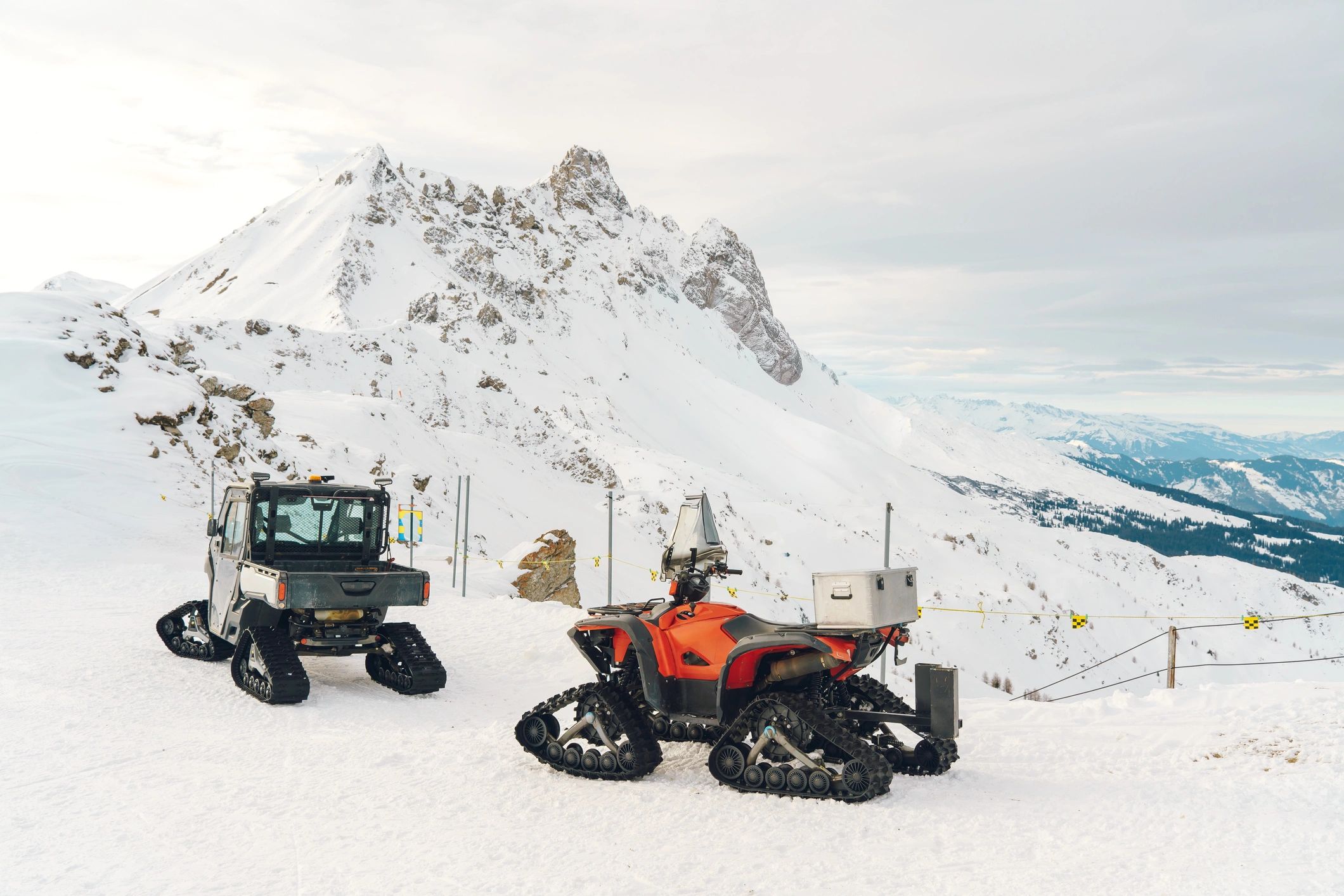 Snow grooming vehicles parked on a snowy mountain landscape